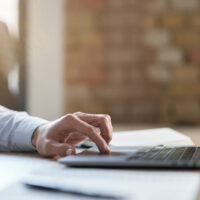 Cropped photo of a laptop on the table with a finger on a touch pad